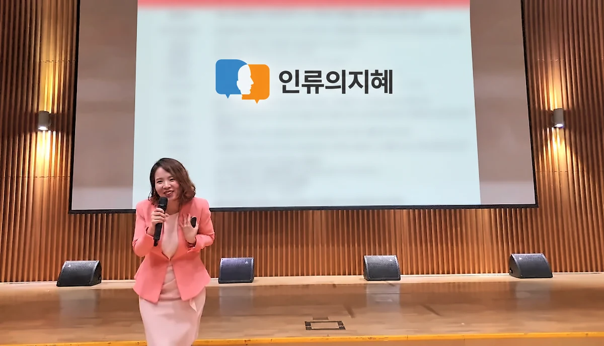 분홍 정장 차림으로 밝게 미소 지으며 강의하는 이현실 대표강사