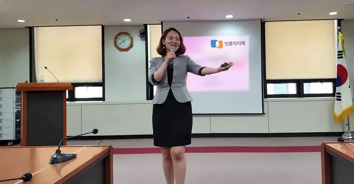 회색 정장 차림으로 마이크를 들고 강의하는 이현실 대표강사